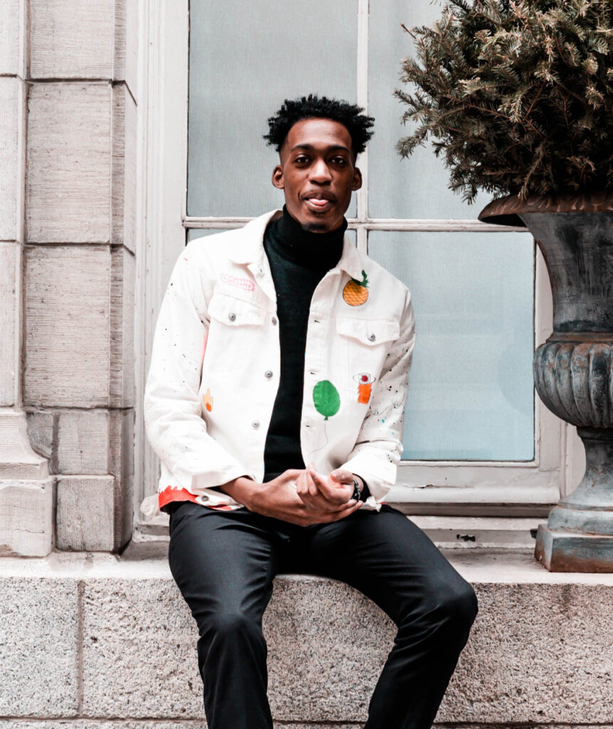 Photo of a black man wearing a white jacket with colorful splotches