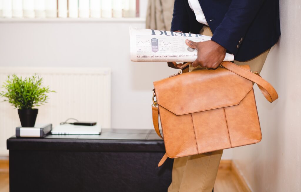 A man holding a briefcase and the business section of the newspaper.