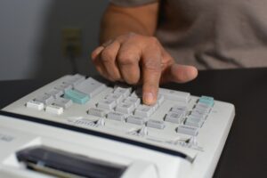 A person typing on a large calculator.