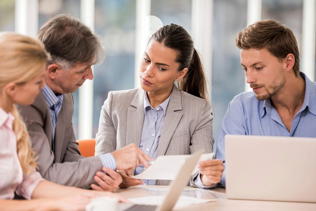 Coworkers sitting around a table discussing documents.