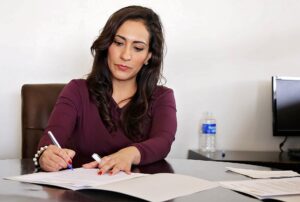 A woman sitting at a desk examining papers.