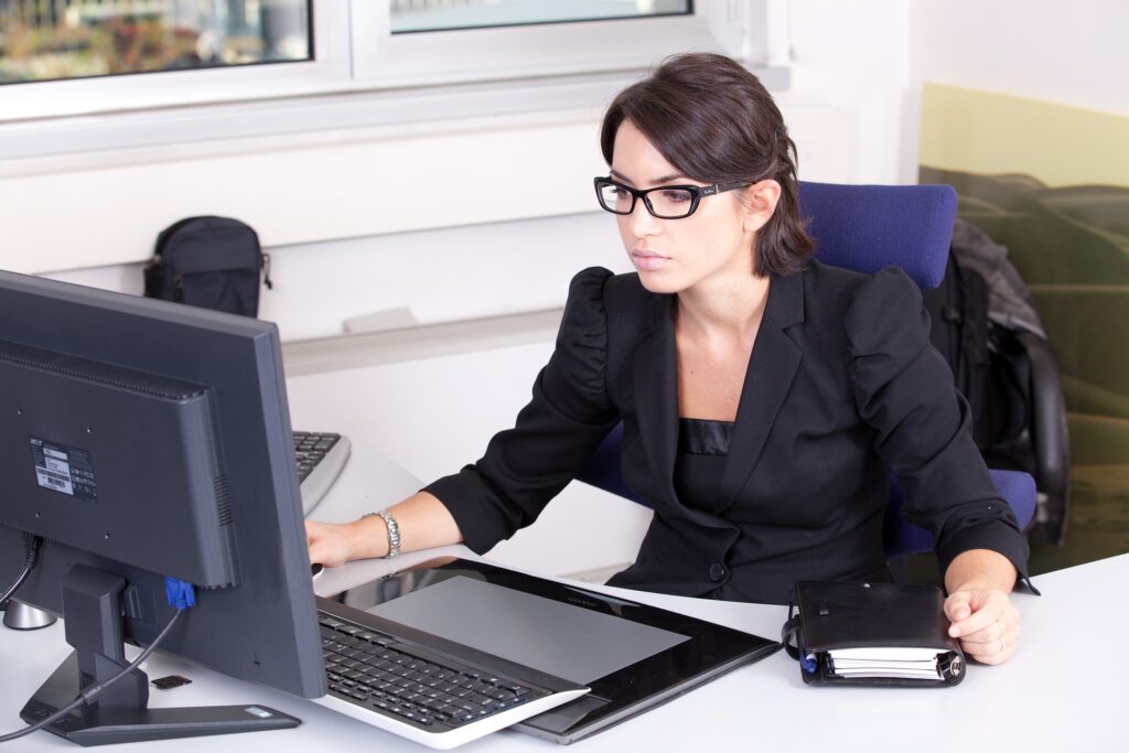 A white woman sitting in front of a computer on a desk.