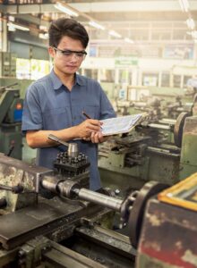 A worker holding a clipboard in a factory.